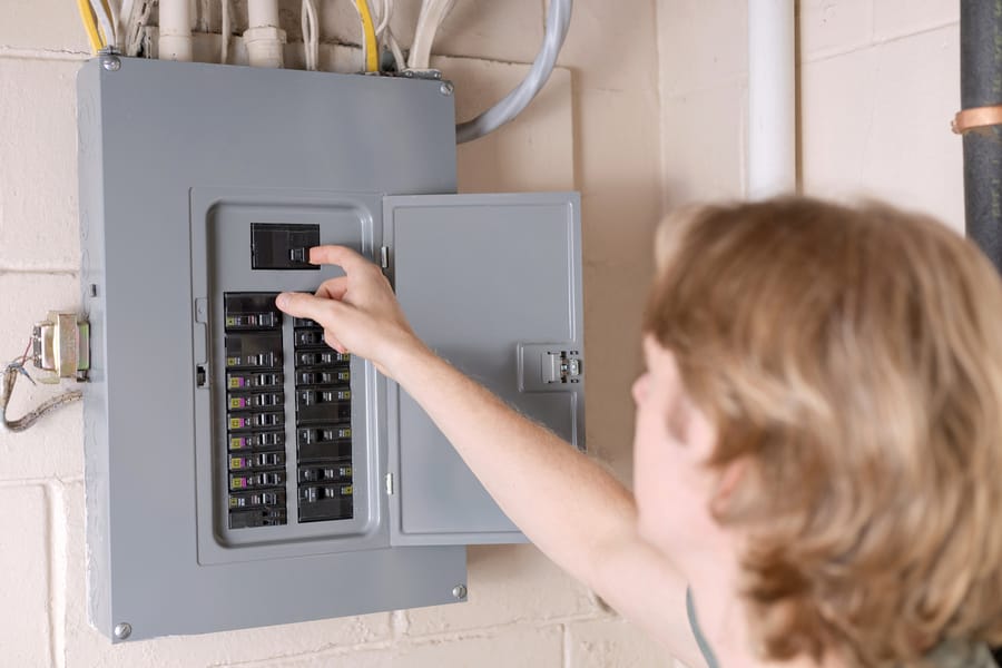 A man is shutting off the main circuit breaker on electrical panel
