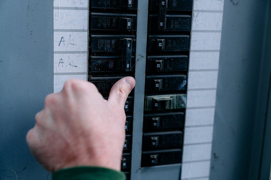 Electrician placing thumb over electrical panel switch