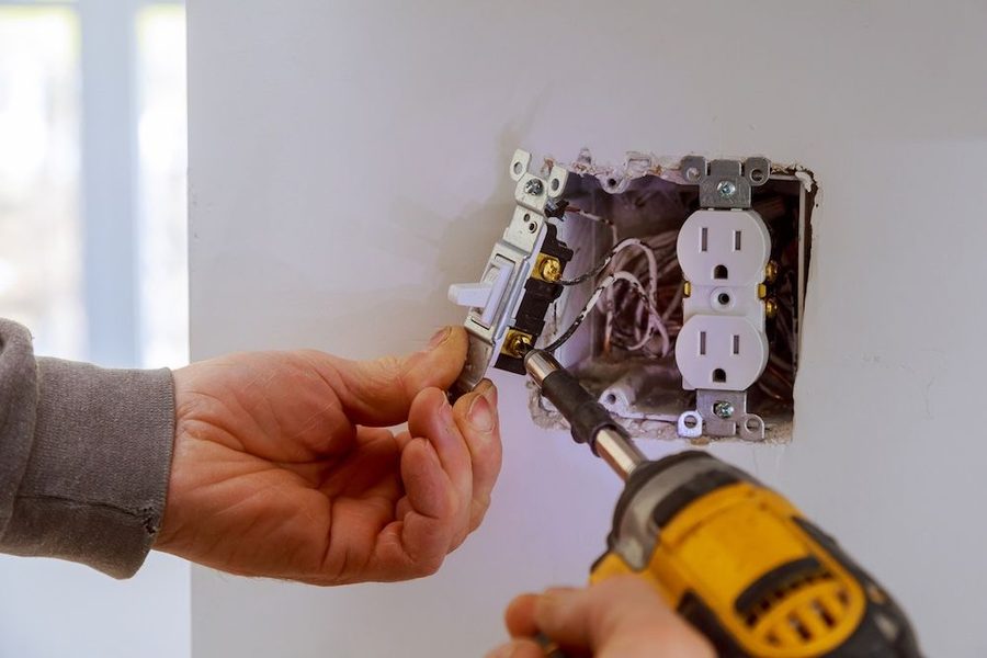 Electrician repairing a wall outlet